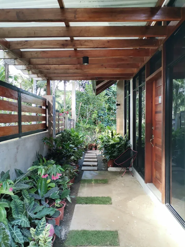 A covered timber-and-glass walkway lined with potted plants and stepping stones leading through the garden