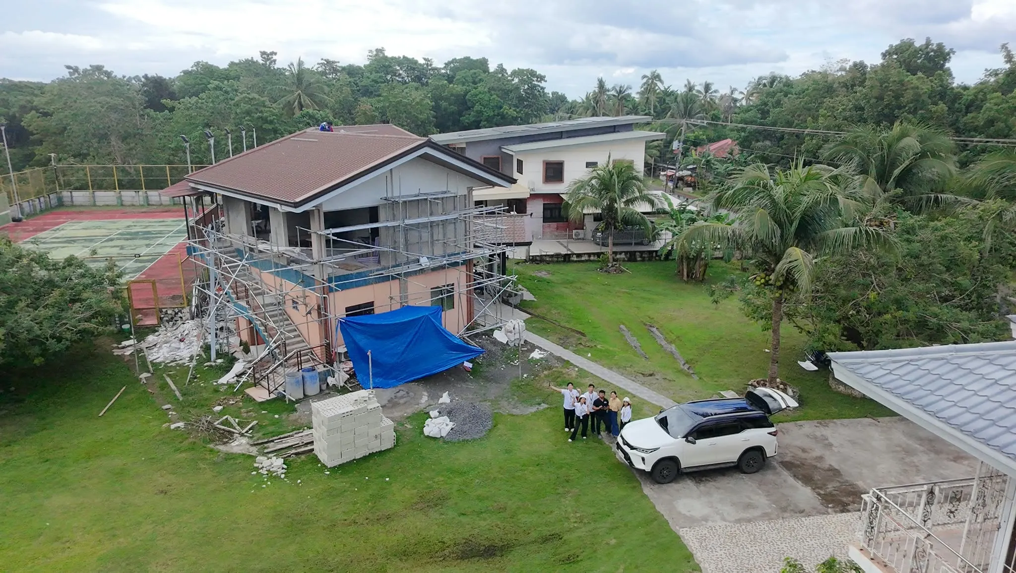 Aerial view of an A.M Architects+ construction site in Bohol with scaffolding up and the team waving beside their vehicle