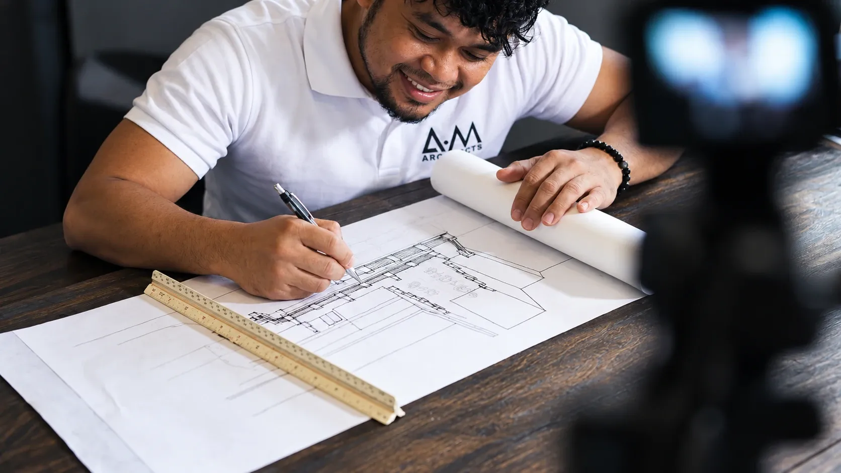 Architect Alberto Macabudbud smiling as he sketches a building elevation by hand